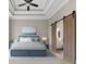 Relaxing primary bedroom with a tray ceiling, ceiling fan, and modern barn door to the bathroom at 6454 Meridian Way, Atlanta, GA 30328