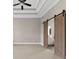 Spacious primary bedroom with a tray ceiling, ceiling fan, and a view of the bathroom through barn doors at 6454 Meridian Way, Atlanta, GA 30328