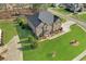 Aerial view of a well-manicured lawn, trees, and a brick home with gray roof at 4580 Cloister Cir, Hampton, GA 30228
