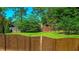 Fenced backyard with lush green grass and mature trees, featuring a wooden storage shed at 925 Wynn Rd, Mcdonough, GA 30252