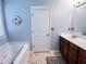 Bright bathroom featuring a soaking tub, vanity with cabinets, and ceramic tile floors at 925 Wynn Rd, Mcdonough, GA 30252