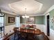 Traditional dining room featuring a detailed trey ceiling, wood table, and adjacent wet bar at 925 Wynn Rd, Mcdonough, GA 30252