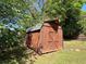 Wooden storage shed in a backyard, surrounded by lush greenery and a chain-link fence at 925 Wynn Rd, Mcdonough, GA 30252