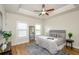 Bright main bedroom featuring a tray ceiling, ceiling fan, and hardwood floors at 1323 Faircrest Way, Suwanee, GA 30024