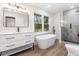 Elegant bathroom featuring soaking tub, frameless glass shower, and large vanity with modern fixtures at 3185 Hammarskjold Dr, East Point, GA 30344