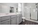 Bright bathroom featuring a double sink vanity with gray cabinets and a glass enclosed shower at 515 Vandenburg Dr, Villa Rica, GA 30180