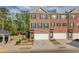 Three-story brick townhome featuring an attached garage and well-maintained landscaping with a gazebo in the background at 2042 Clay Rd, Snellville, GA 30078