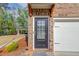 Up close, brick townhome featuring a front door with glass panes and a white garage door, and wooden supports above door at 2042 Clay Rd, Snellville, GA 30078