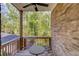 Covered back porch with brick walls, ceiling fan, wrought iron table and chairs overlooking wooded backyard at 2042 Clay Rd, Snellville, GA 30078