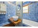 This blue-tiled bathroom has a modern sink, wood shelf, and a stylish mirror at 1015 S Candler St, Decatur, GA 30030