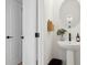 Modern powder room features a pedestal sink, round mirror, and sleek black fixtures at 440 Carrera Ln, Acworth, GA 30102