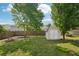 Backyard with green grass, a wooden fence, mature trees, a storage shed and a fire pit at 5450 Fieldfreen Dr, Cumming, GA 30028