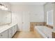 Bathroom featuring dual sinks, framed mirror, tub and a separate shower at 5450 Fieldfreen Dr, Cumming, GA 30028