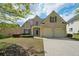 Brick home with a two-car garage, lush lawn, and beautifully landscaped front yard at 5450 Fieldfreen Dr, Cumming, GA 30028
