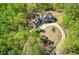 Aerial view showcases a stunning home with lush landscaping and a circular driveway surrounded by dense trees at 1000 Holly St, Canton, GA 30114