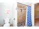 Bathroom including a tiled shower with blue patterned curtain, toilet, tile flooring, and an adjacent doorway at 1000 Holly St, Canton, GA 30114