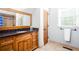 Bathroom features a wood vanity with granite top, framed mirror, and a door to the toilet and shower at 1000 Holly St, Canton, GA 30114