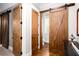 Hallway features hardwood floors, wooden barn doors, and leads to an open bathroom at 1000 Holly St, Canton, GA 30114