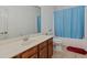 Simple bathroom with a single sink vanity and shower tub with blue curtain at 265 Lily Cove Dr, Loganville, GA 30052
