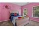 Bedroom featuring pink walls, carpet flooring, and a bed with striped bedding next to two windows at 265 Lily Cove Dr, Loganville, GA 30052