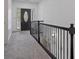 Upstairs hallway with neutral carpet and decorative iron railings, leading to the front door at 265 Lily Cove Dr, Loganville, GA 30052