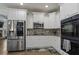 Spacious kitchen featuring stainless steel appliances, tile backsplash, and white cabinetry at 265 Lily Cove Dr, Loganville, GA 30052
