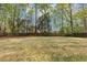 View of the spacious backyard with a manicured lawn, mature hardwood trees, and a wood fence at 1960 Barnes Mill Rd, Marietta, GA 30062
