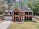Aerial shot of the red brick two-story home with a dormer, black shutters, an attached garage, and a driveway at 1960 Barnes Mill Rd, Marietta, GA 30062