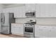 Well-lit kitchen featuring stainless steel appliances, white cabinets, and wood-look flooring at 269 Shoals Bridge Rd, Acworth, GA 30102