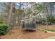 Backyard featuring a trampoline with safety net and lush green landscaping at 107 Grand Ave, Suwanee, GA 30024