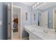 Bathroom with light blue walls, white vanity, and mirror; hallway leading to a bedroom can be seen in the background at 107 Grand Ave, Suwanee, GA 30024