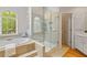 Bathroom with soaking tub, glass shower, and an arched window bringing in light at 107 Grand Ave, Suwanee, GA 30024