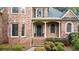 Elegant brick home featuring a covered front porch, complemented by manicured landscaping and charming architectural details at 107 Grand Ave, Suwanee, GA 30024