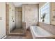 Bright bathroom featuring tiled shower, soaking tub, and ample sunlight at 192 Palisade Point Dr, Ellenwood, GA 30294