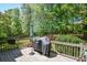 Wood deck area with grill, umbrella and fenced perimeter surrounded by mature trees at 210 Mels Way, Stockbridge, GA 30281