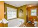 Bright bathroom with a large soaking tub, olive colored walls, and a window with a floral valance at 210 Mels Way, Stockbridge, GA 30281