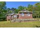 Charming brick home featuring a well-maintained lawn and complemented by lush trees under a clear sky at 210 Mels Way, Stockbridge, GA 30281