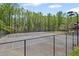 Outdoor tennis court surrounded by a chain link fence and lush greenery at 7425 Twin Creek Ct, Cumming, GA 30041