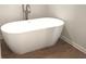 Freestanding modern bathtub with elegant fixtures and warm wood-look tile flooring in a relaxing bathroom at 1594 Sungrown Way, Mcdonough, GA 30253