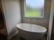 Bright bathroom featuring a modern soaking tub beneath a frosted window at 1594 Sungrown Way, Mcdonough, GA 30253