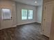 A bright living room with wood-look flooring, large windows, and a door leading outside at 1594 Sungrown Way, Mcdonough, GA 30253