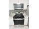 Close-up of a modern gas range with stainless steel microwave, granite countertops, and white cabinets at 705 Windchase Ln, Stone Mountain, GA 30083