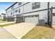 View of the townhouse featuring a white garage door with concrete driveway and green yard space at 823 Mackay Crk, Woodstock, GA 30188