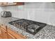 Close-up of a stainless steel stove top with gray granite counters and white subway tile backsplash at 823 Mackay Crk, Woodstock, GA 30188