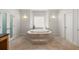 Bathroom area featuring a large soaking tub surrounded by beige tile and a window at 1159 Thornwell Ne Dr, Brookhaven, GA 30319