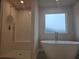 Bathroom featuring a freestanding tub, a tiled shower with a bench, and a frosted glass window at 1636 Fuma Leaf Way, Mcdonough, GA 30253