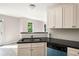 Kitchen with stainless steel dishwasher and sink, neutral-colored cabinets, and black granite countertops at 960 Revere Way, Hampton, GA 30228