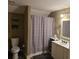 Modest bathroom with a toilet, sink with cabinets, and shower with a gray curtain at 278 Mission Oak Se Dr, Grayson, GA 30017