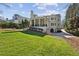 Spacious backyard with lush green lawn, mature trees, covered porch, and an exterior view of the home at 3114 Peachtree Ne Dr, Atlanta, GA 30305