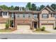 Charming brick and stone townhome featuring a two-car garage, manicured landscaping, and a welcoming entrance at 1983 Silver Birch Se Dr, Smyrna, GA 30080